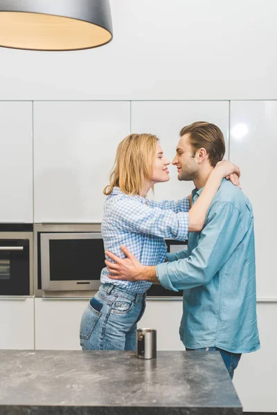 Vista lateral de casal afetuoso abraçando uns aos outros em casa — Fotografia de Stock