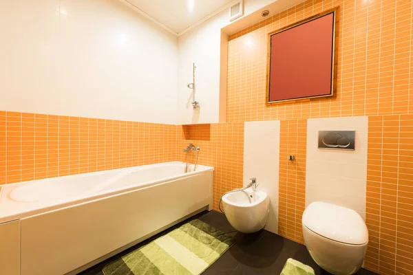 Вид на современную ванную комнату в оранжевых и белых цветах — стоковое фото
