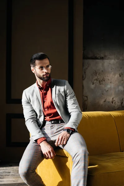 Modisch eleganter Mann in Brille und Anzug sitzt auf der Couch — Stockfoto