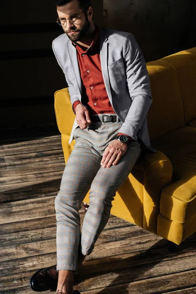 Красивый стильный элегантный мужчина сидит на диване — стоковое фото