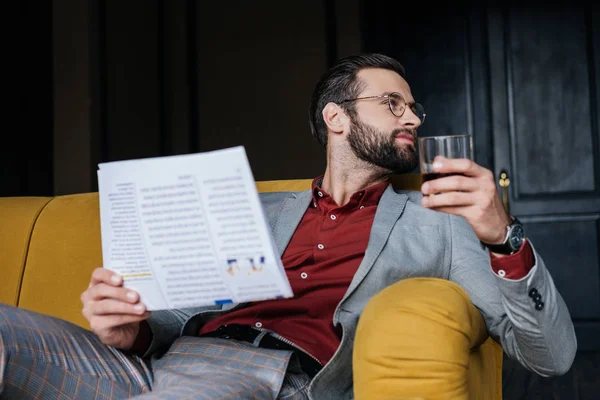 Elegante hombre sosteniendo periódico y vaso de coñac - foto de stock