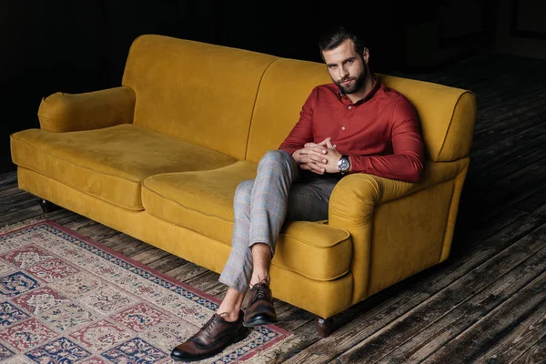 Homme élégant à la mode assis sur le canapé jaune — Photo de stock