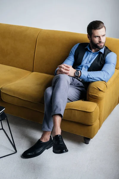 Homme élégant assis sur le canapé jaune — Photo de stock