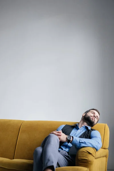 Красивий стильний чоловік відпочиває на жовтому дивані — стокове фото