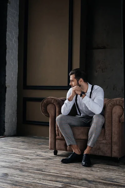 Kaukasischer nachdenklicher stilvoller Mann sitzt im Sessel im Loft-Interieur — Stockfoto
