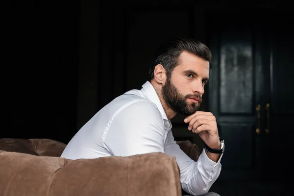 Thoughtful handsome bearded man sitting in armchair — Stock Photo