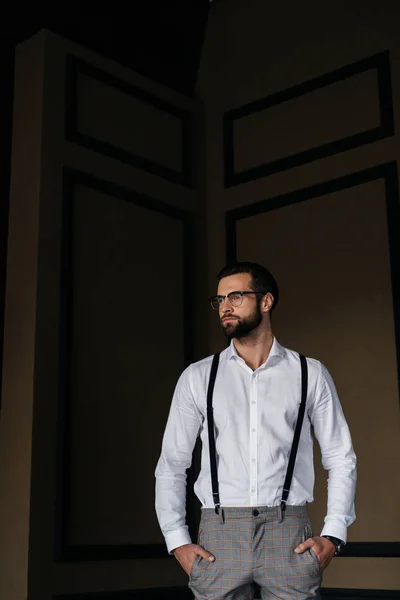 Красивый элегантный мужчина позирует в белой рубашке и подтяжках — стоковое фото