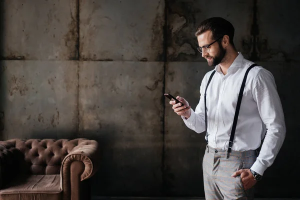 Hombre barbudo de moda en tirantes con teléfono inteligente — Stock Photo