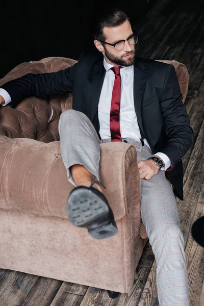 Hombre de negocios guapo en traje elegante posando en sillón - foto de stock