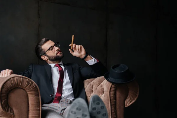 Schöner stylischer Geschäftsmann mit Zigarre posiert im Sessel — Stockfoto