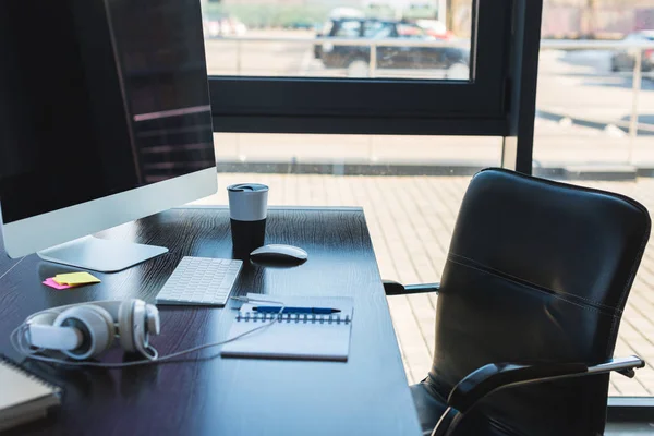 Table with computer and cup of coffee in business office — Stock Photo