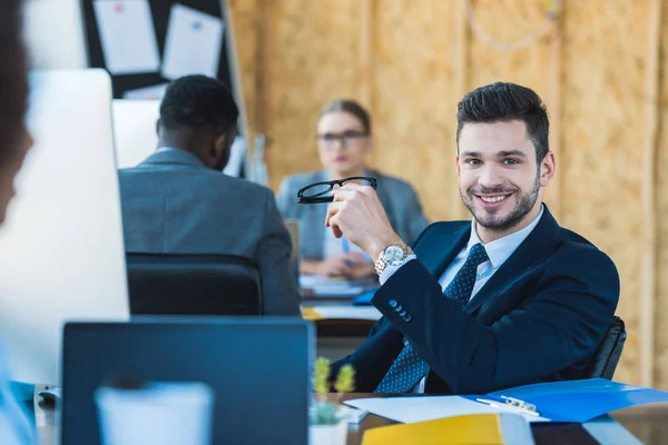 Lächelnder Geschäftsmann blickt im Büro in die Kamera — Stockfoto