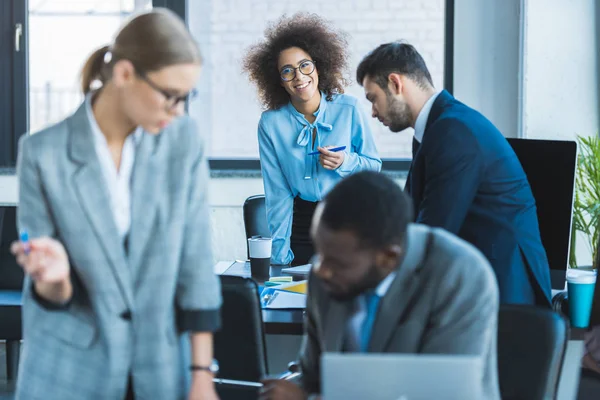 Lächelnde afrikanisch-amerikanische Geschäftsfrau blickt im Büro in die Kamera — Stockfoto