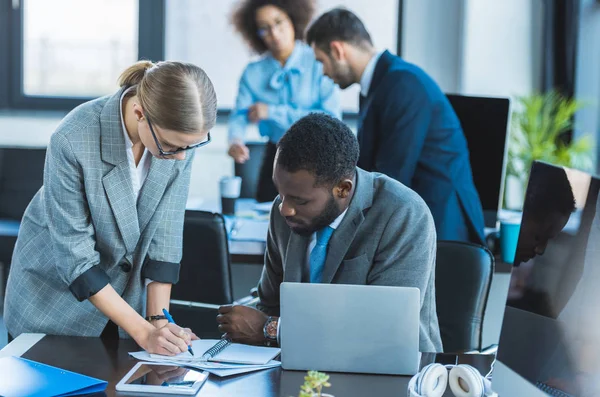 Businesswoman writing something to notebook in office — Stock Photo