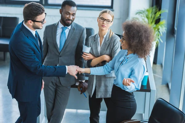 Multicultural businesspeople shaking hands in office — Stock Photo