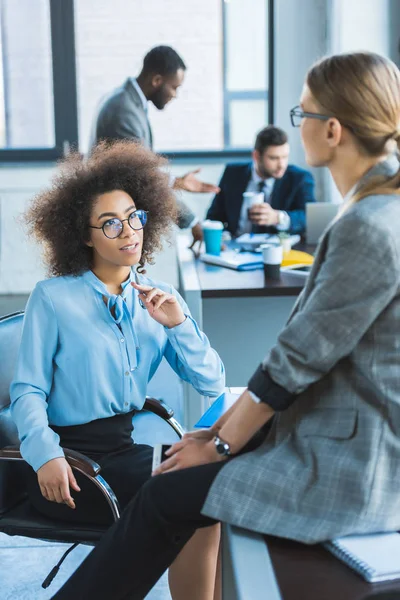 Beautiful multiethnic businesswomen talking in office — Stock Photo