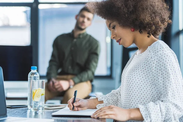 Vista laterale della donna d'affari afro-americana che scrive qualcosa in ufficio — Foto stock