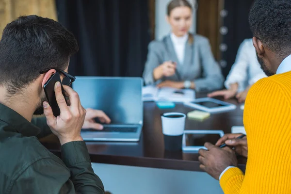 Uomo d'affari che parla tramite smartphone e utilizza il computer portatile in ufficio — Foto stock