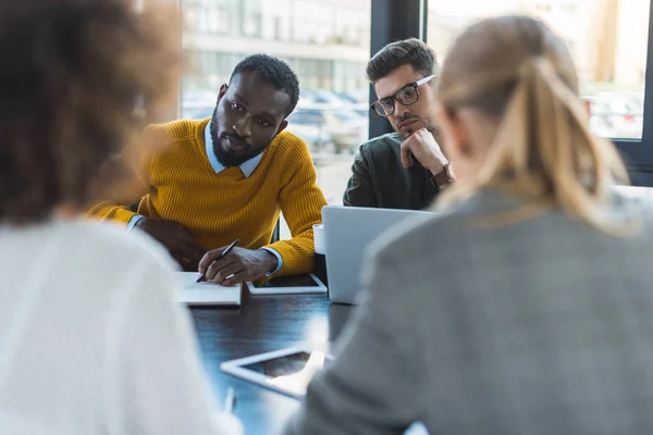 Multicultural businesspeople sitting at table in office — Stock Photo