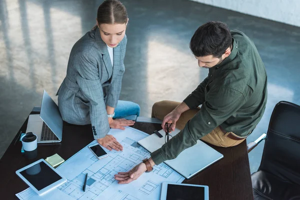 Vista de ángulo alto del hombre de negocios que muestra algo en el plano de la mujer de negocios - foto de stock