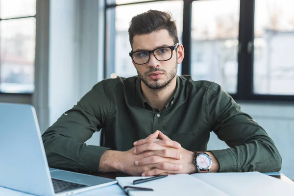 Homme d'affaires assis à table dans le bureau et regardant la caméra — Photo de stock