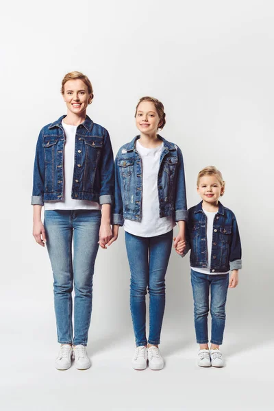 Glückliche Familie in ähnlicher Jeanskleidung in Reihe stehend und Händchen haltend auf grau isoliert — Stockfoto