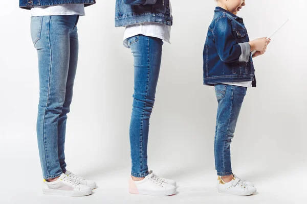 Partial view of family and kid with tablet in similar denim clothing standing in row isolated on grey — Stock Photo