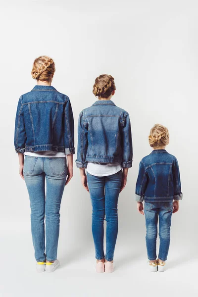 Back view of family in similar denim clothing standing in row isolated on grey — Stock Photo