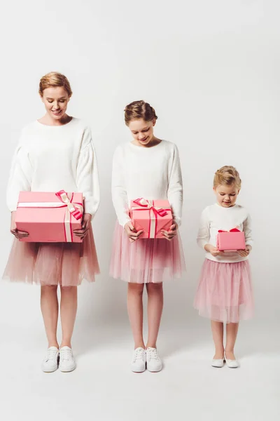 Mãe sorridente e filhas pequenas em saias de tule tutu rosa semelhante com presentes embrulhados isolados em cinza — Fotografia de Stock