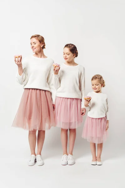 Familia en ropa similar con rosquillas dulces aisladas en gris - foto de stock