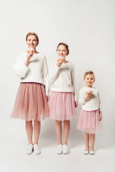 Familie in ähnlicher Kleidung mit süßen Donuts isoliert auf grau — Stockfoto