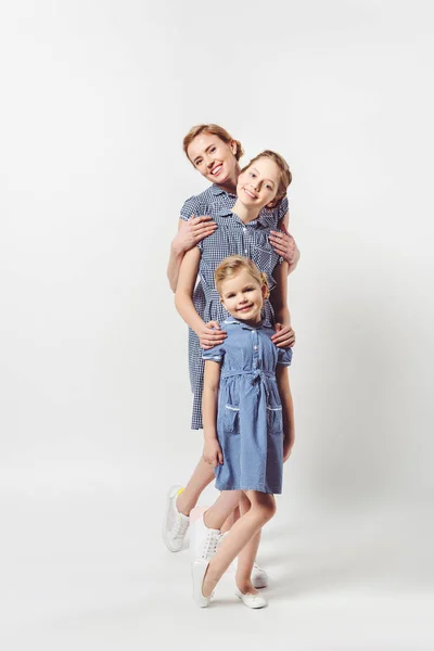 Mère et filles souriantes dans des robes similaires isolées sur gris — Photo de stock