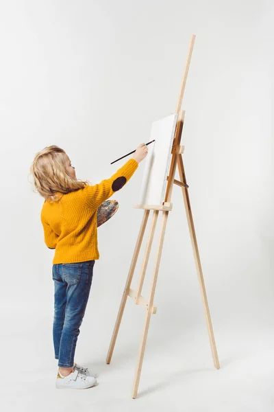 Beautiful little child painting on canvas with oil paint on white — Stock Photo