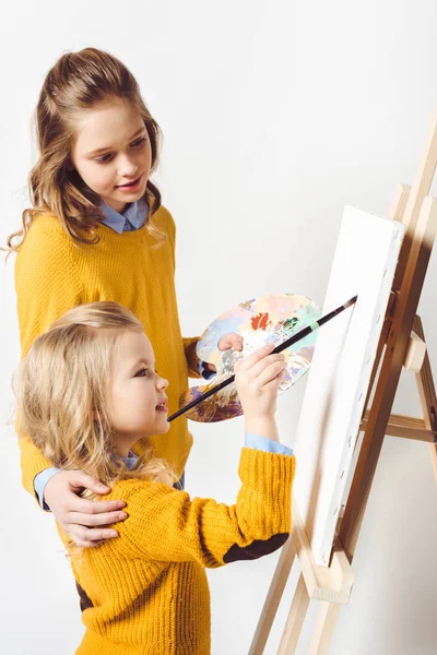 Sisters of different generations painting on blank canvas — Stock Photo