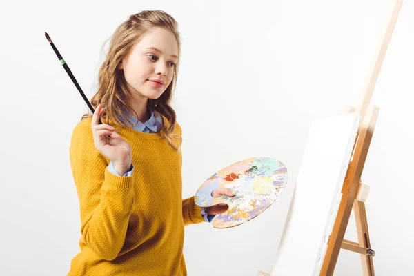 Hermosa adolescente pintora en suéter amarillo con pincel de pintura y paleta - foto de stock
