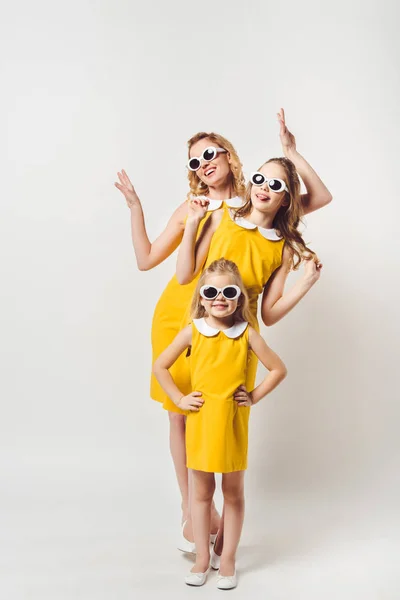 Beautiful posing mother and daughters in similar retro style yellow dresses on white — Stock Photo