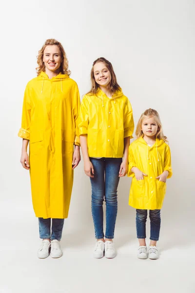 Mère et filles en imperméables jaunes sur blanc — Photo de stock