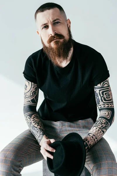 Handsome bearded tattooed man looking at camera on white — Stock Photo