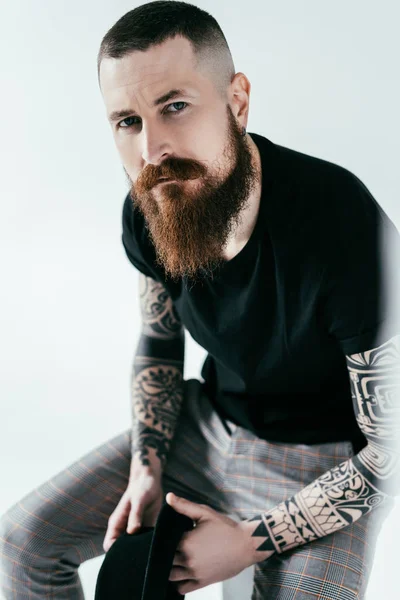 Handsome bearded tattooed man looking at camera on white — Stock Photo
