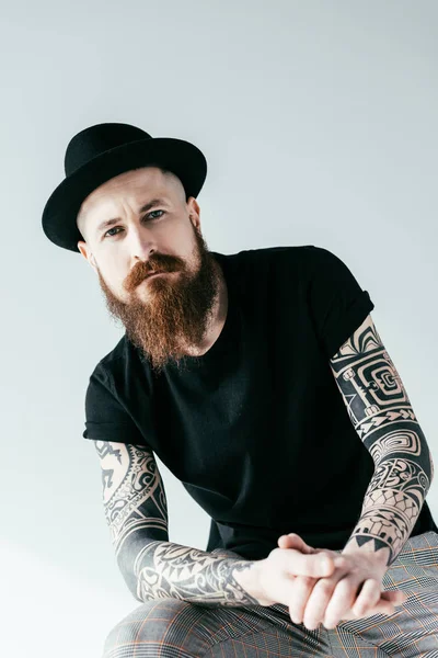 Bearded tattooed man in hat looking at camera isolated on white — Stock Photo