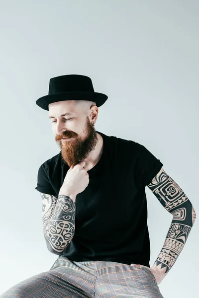 Guapo hombre tatuado tocando la barba aislado en blanco - foto de stock