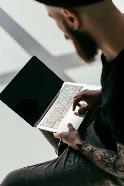 Vue grand angle de l'homme tatoué barbu en utilisant un ordinateur portable sur blanc — Photo de stock