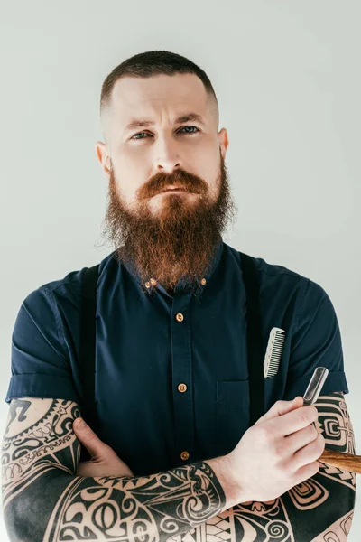 Hombre tatuado sosteniendo la navaja y mirando a la cámara aislada en blanco — Stock Photo