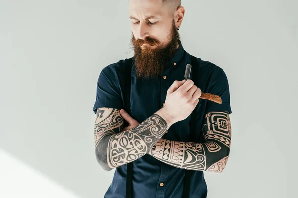 Hombre tatuado sosteniendo la navaja con los ojos cerrados - foto de stock