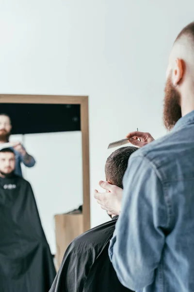 Barber combing customer hair at barbershop isolated on white — Stock Photo