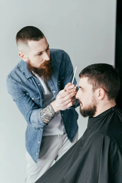 Side view of barber cutting customer hair at barbershop isolated on white — Stock Photo