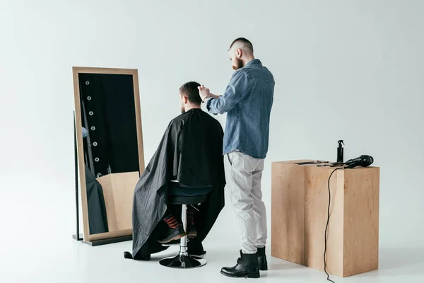 Barber shaving customer hair in front of mirror at barbershop — Stock Photo