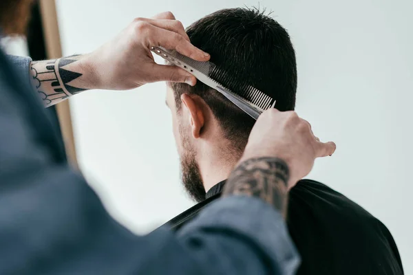 Image recadrée de coiffeur coupe les cheveux du client au salon de coiffure isolé sur blanc — Photo de stock