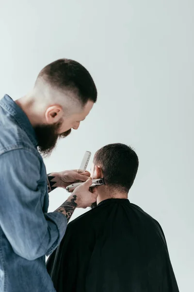 Rear view of barber shaving customer hair at barbershop isolated on white — Stock Photo