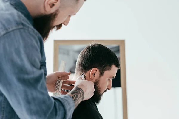 Vista laterale del barbiere barba capelli dei clienti al negozio di barbiere isolato su bianco — Foto stock
